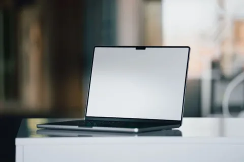 Seseorang sedang bekerja menggunakan gadget laptop dan smartphone di meja kerja modern