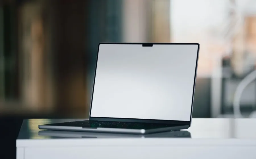 Seseorang sedang bekerja menggunakan gadget laptop dan smartphone di meja kerja modern