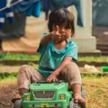 Seorang anak perempuan tersenyum percaya diri saat bermain menyusun balok kayu di rumah