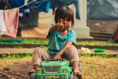 Seorang anak perempuan tersenyum percaya diri saat bermain menyusun balok kayu di rumah