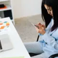 Seseorang sedang menggunakan smartphone produktivitas kerja untuk memeriksa dokumen kantor di meja kerja