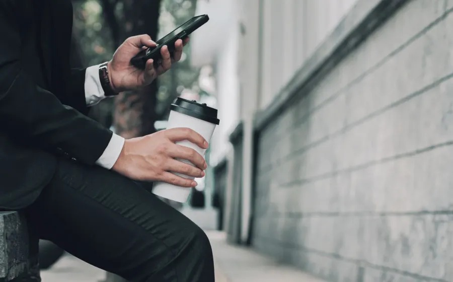 Seseorang menggunakan smartphone untuk kerja sambil memeriksa dokumen dan aplikasi kantor