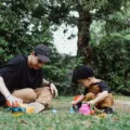 Ayah dan anak balita sedang asyik bermain miniatur mobil di lantai rumah untuk mengenal transportasi
