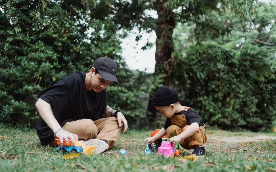 Ayah dan anak balita sedang asyik bermain miniatur mobil di lantai rumah untuk mengenal transportasi