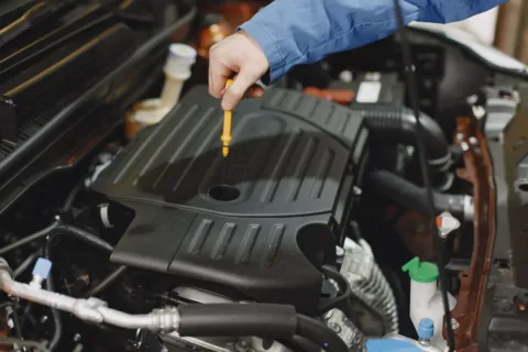 Cara merawat mobil secara rutin dengan memeriksa level oli mesin menggunakan dipstik